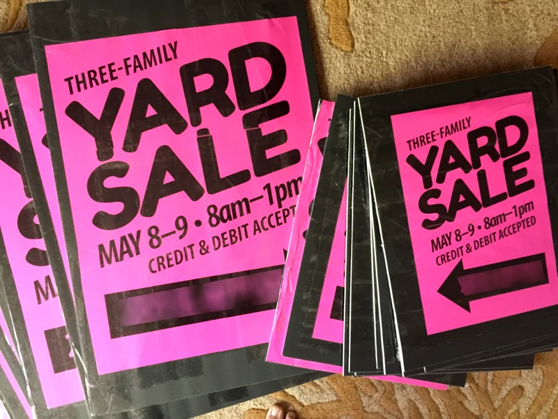 Bright printed yard sale signs on wire stands